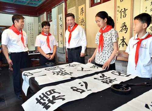 2014年5月30日上午，中共中央總書記、國家主席、中央軍委主席習近平來到北京市海淀區(qū)民族小學，參加慶祝“六一”國際兒童節(jié)活動。這是習近平觀看學生書寫的毛筆字。新華社記者 李濤 攝