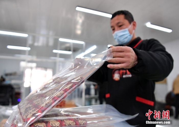 1月18日，雄安新區(qū)大樹劉莊村辛愛青家中的冰糖葫蘆加工廠，工人正對(duì)冰糖葫蘆半成品進(jìn)行真空塑封。作為遠(yuǎn)近聞名的“冰糖葫蘆村”，大樹劉莊村制作冰糖葫蘆的歷史已有100多年，全村三分之二的村民都會(huì)這門手藝，吸引不少游客慕名而來。 中新社記者 韓冰 攝